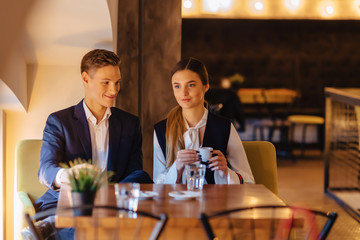 A stylish couple drinks morning coffee at the cafe, young businessmen and freelancers