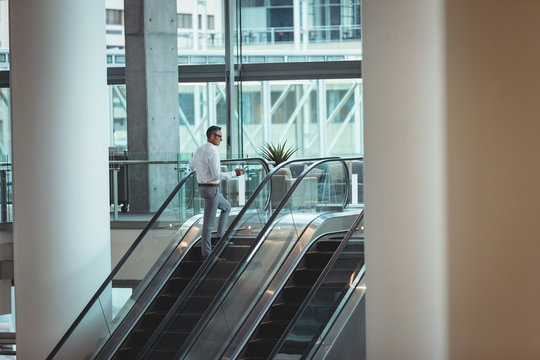 Businessman ascending escalator in the office