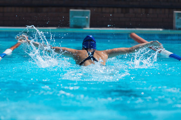 Young female swimmer with swim goggle swimming at swimming pool 