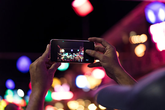 Young Asian traveler taking photo with mobile phone in pub and street road at night in Cambodia