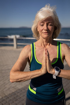 Active senior woman performing yoga on a promenade in the sunshine