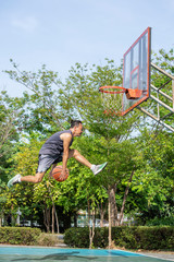 Basketball in hand man jumping Throw a basketball hoop Background  tree in park.
