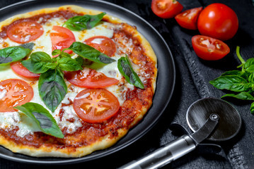 pizza with tomatoes on black background