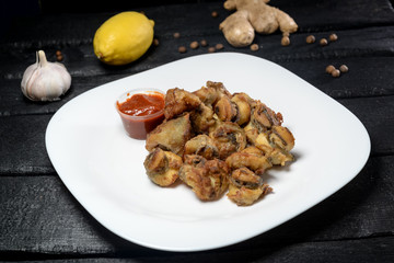 fried rapana with sauce in a white plate on a black background