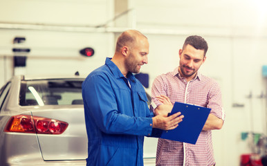 auto service, repair, maintenance and people concept - mechanic with clipboard talking to man or...