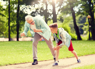 family, generation and people concept - happy grandfather and grandson racing at summer park