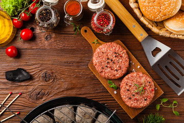 Raw beef burger, ready for grilling. Grill accessories. Concept. Free space for description. Top view.