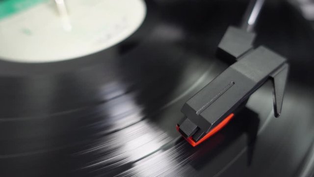 Gramophone stylus on vinyl record LP / a phonograph pickup or a transducer on a turntable. Black musical long play album disc 12 inch 33 rpm spiral groove. Stereo sound playback. 4K UHD closeup view.