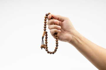 Hand holding a muslim rosary beads or Tasbih on white background. Copy space and selective focus