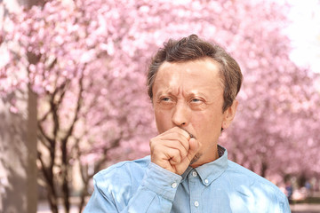 Man having asthma attack outdoors on spring day