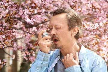 Obraz premium Man with inhaler having asthma attack on spring day