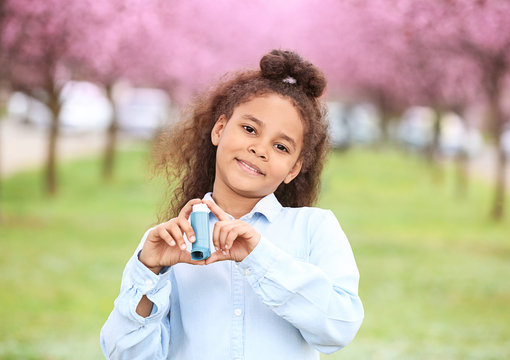 African-American girl with inhaler outdoors on spring day