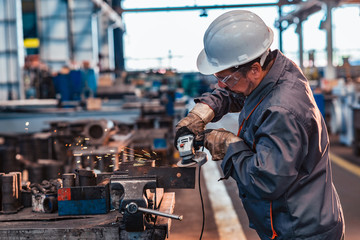 Skilled industrial worker grinding metal part. - Powered by Adobe