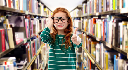education, vision and reading concept - smiling red haired student girl in glasses and green striped shirt over library background