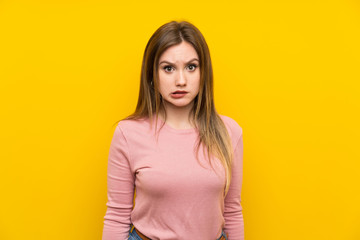 Fototapeta premium Teenager girl over isolated yellow background having doubts and with confuse face expression