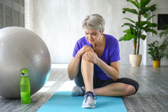 Sporty Mature Woman With Injured Knee After Training At Home