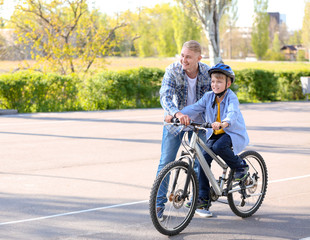 Fototapeta premium Father teaching his son to ride bicycle outdoors
