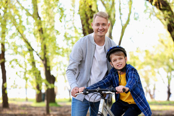 Fototapeta premium Father teaching his son to ride bicycle outdoors