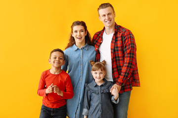 Happy couple with little adopted children on color background