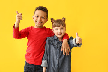 Portrait of cute children showing thumb-up on color background