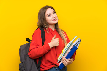 Teenager student girl over yellow background giving a thumbs up gesture