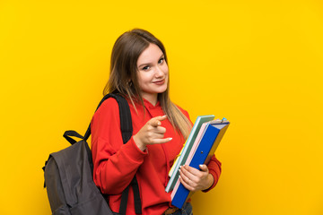 Teenager student girl over yellow background points finger at you - obrazy, fototapety, plakaty