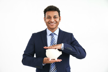 Handsome businessman with piggy bank on white background