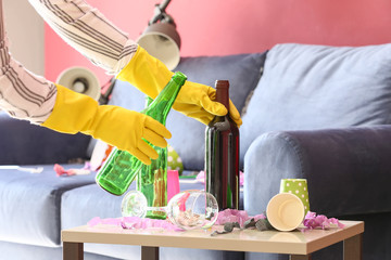 Woman cleaning room in terrible mess after party