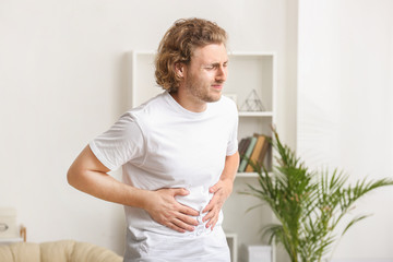 Young man suffering from abdominal pain at home