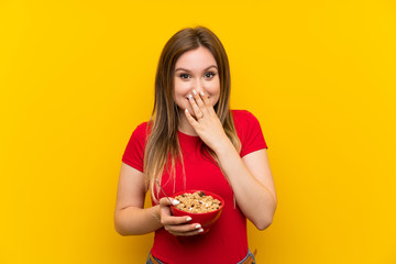 Young teenager girl holding a bowl of cereals with surprise facial expression