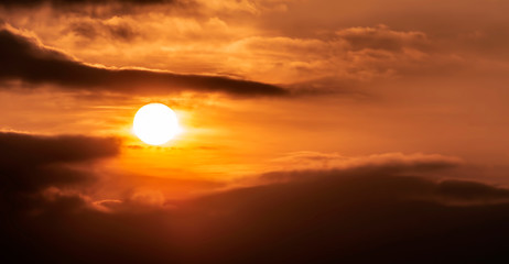 Golden sun in the clouds during sunset.