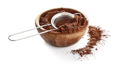 Bowl with cocoa powder and sieve on white background