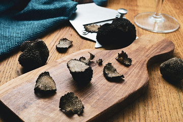 Black truffles slices in wooden board