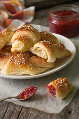 Homemade croissants with berry jam on wooden background