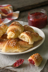 Homemade croissants with berry jam on wooden background