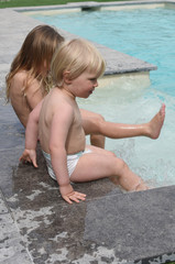 children with feet in the water of a swimming pool