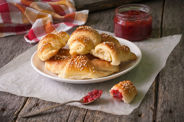 Homemade croissants with berry jam on wooden background