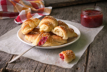Homemade croissants with berry jam on wooden background