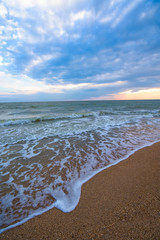 Sunset, moving clouds and sea waves on the beach