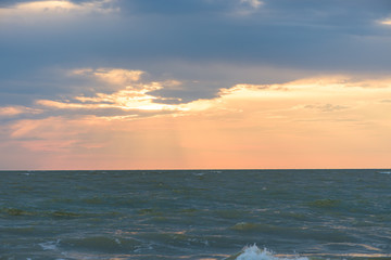 Fototapeta na wymiar Sunset, moving clouds and sea waves on the beach