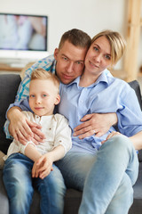 Obraz premium Portret pozytywnej kochającej młodej rodziny siedzi na kanapie w salonie, przystojny ojciec przytulanie żonę i syna