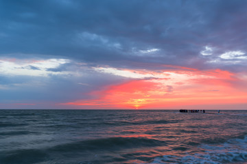 Naklejka na ściany i meble Sunset, moving clouds and sea waves on the beach . long exposure