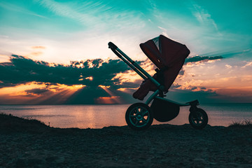 baby carriage stands on the seashore, sunset.