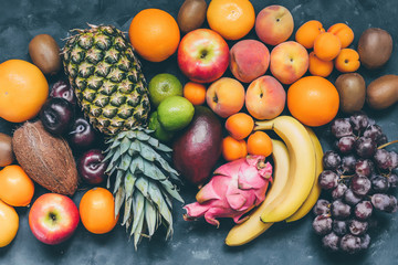 Assortment of fruit pineapple,pitaya,bananas, mango,  grapes, orange, apple, coconut, peaches, apricots, tangerines, lemon and kiwi top view
