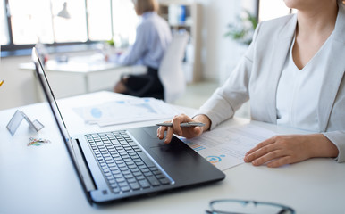 business and people concept - businesswoman with laptop computer and papers working at office