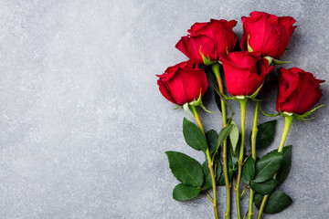 Red roses on grey stone background. Love concept valentines day. Copy space. Top view.