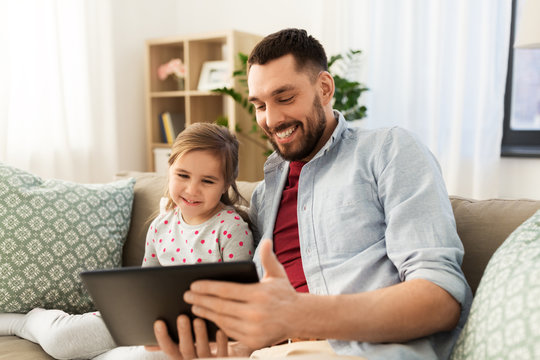 family, fatherhood and technology concept - happy father and little daughter with tablet pc computer at home