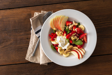 Fruit salad bowl on a wooden table top view. Healthy summer food