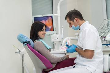 Doctor showing patient how clean teeth on jaw sample