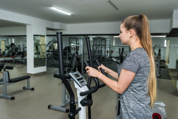 Fototapeta premium Cycling on exercise bikes. The girl is engaged in exercise bike in the gym